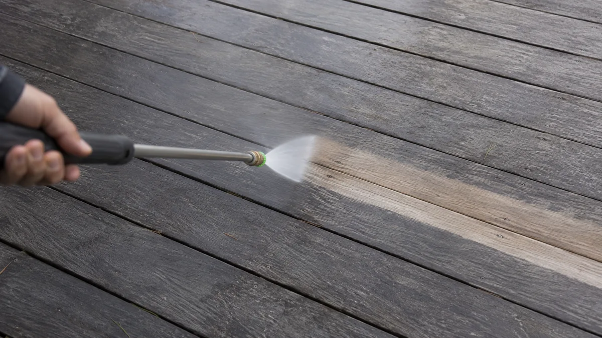 Lance de nettoyeur haute pression en action sur une terrasse en bois grisée