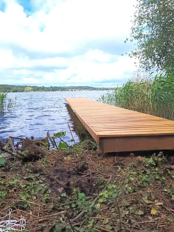 Ponton en bois avançant sur un lac, vu depuis la berge