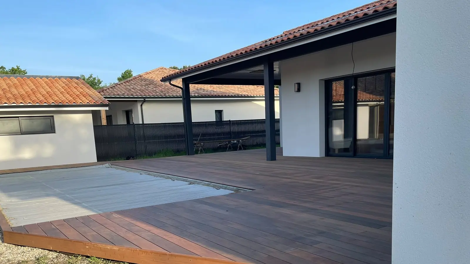 Terrasse en bois exotique posée devant une maison contemporaine avec piscine, réalisée par Sol et Bois